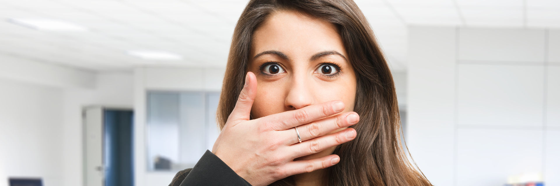 young woman covering her mouth with her hand due to halitosis
