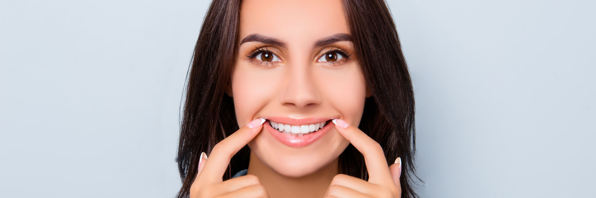 Smiling woman pointing at her beautiful teeth.