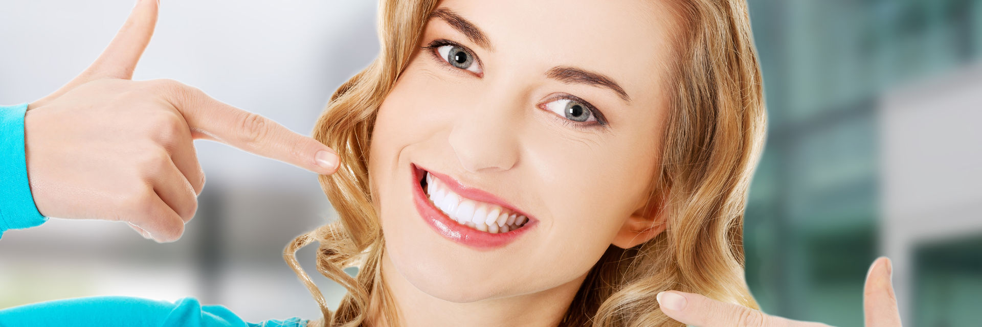 Happy young woman pointing at her beautiful whitened teeth