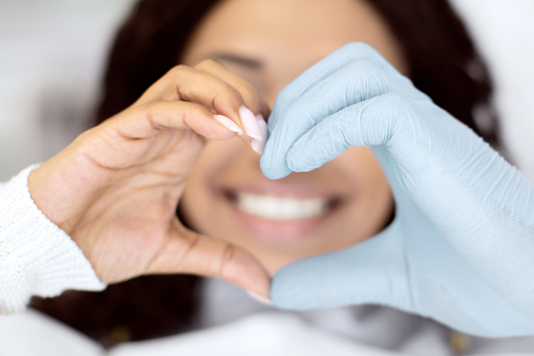 closeup of dentist doctor and female patient making a heart