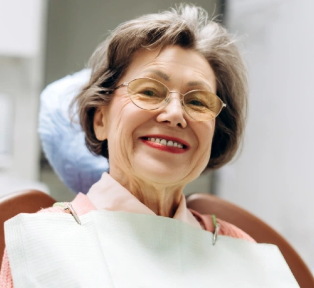 Smiling senior patient seated in a dental chair during a gentle dental cleaning procedure.
