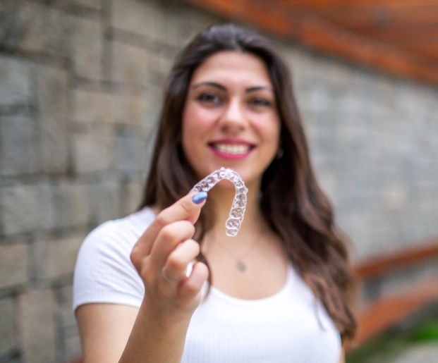Patient displaying a transparent dental aligner as part of modern Invisalign treatment.